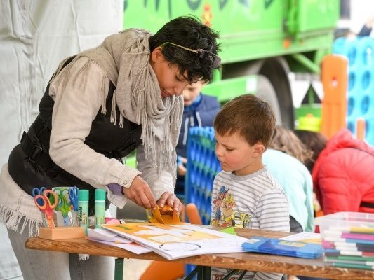 Eine Frau hilft einem kleinen Jungen dabei ein Bild zu malen.