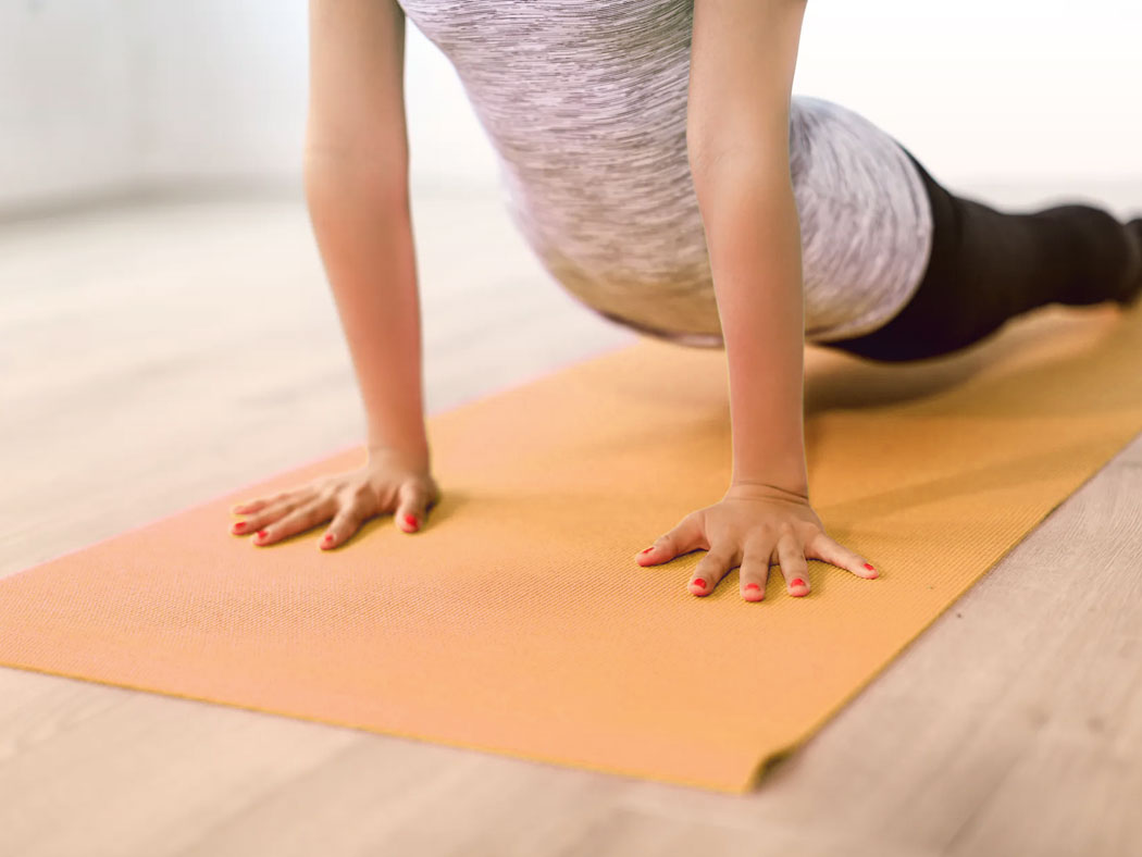 Eine Frau, die gerade eine Yogaübung auf einer Yogamatte macht.