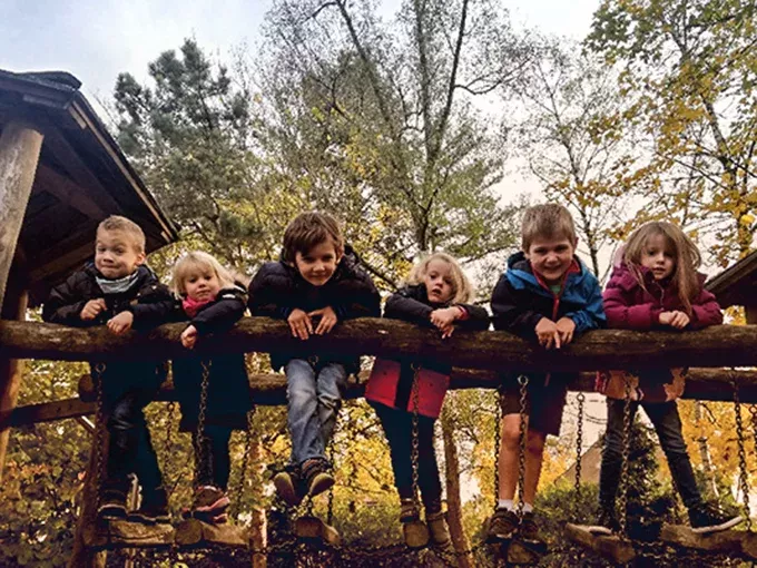 Mehrere Kinder, die auf Klettergerüst posieren. Sie stehen auf der Brücke und lehnen sich über die Brüstung.