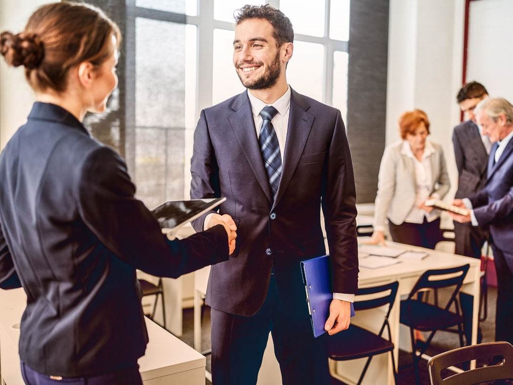 ZWei Personen, die sich bei einem Meeting die Hände schütteln. 