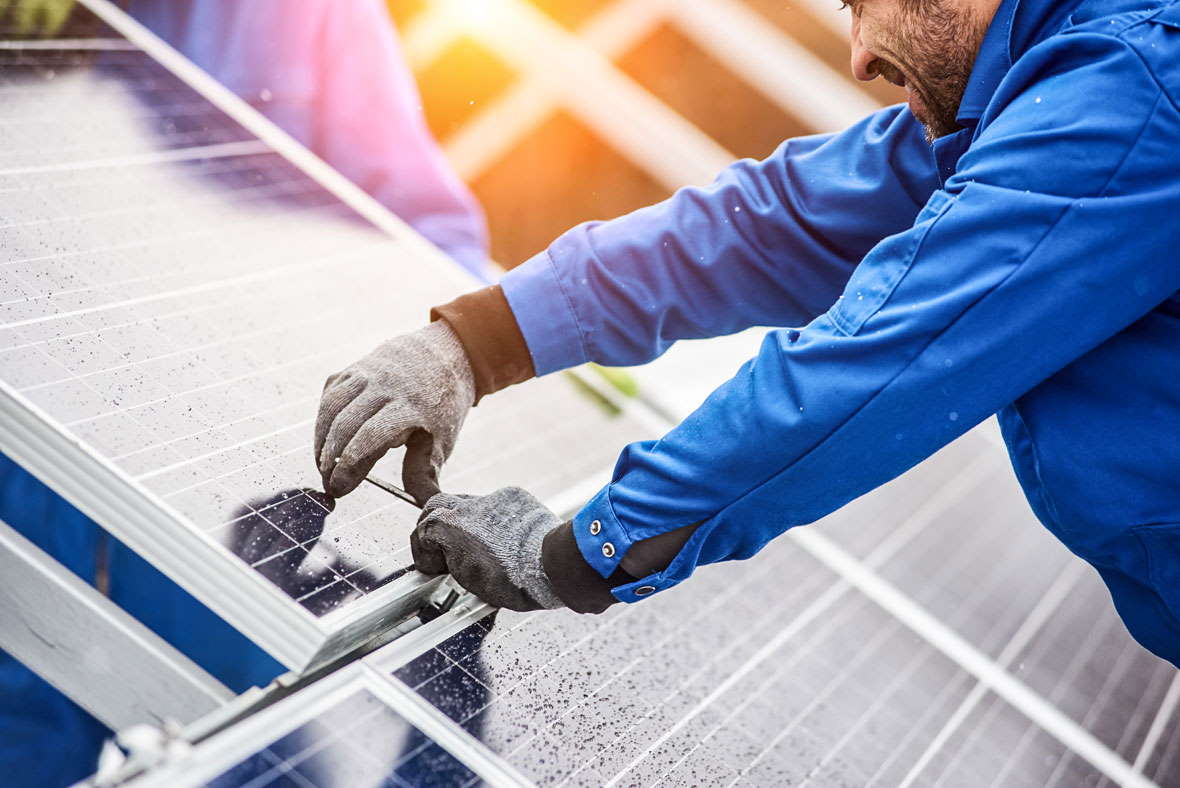 Ein Arbeiter vermisst gerade Solarpanels auf einem Dach.