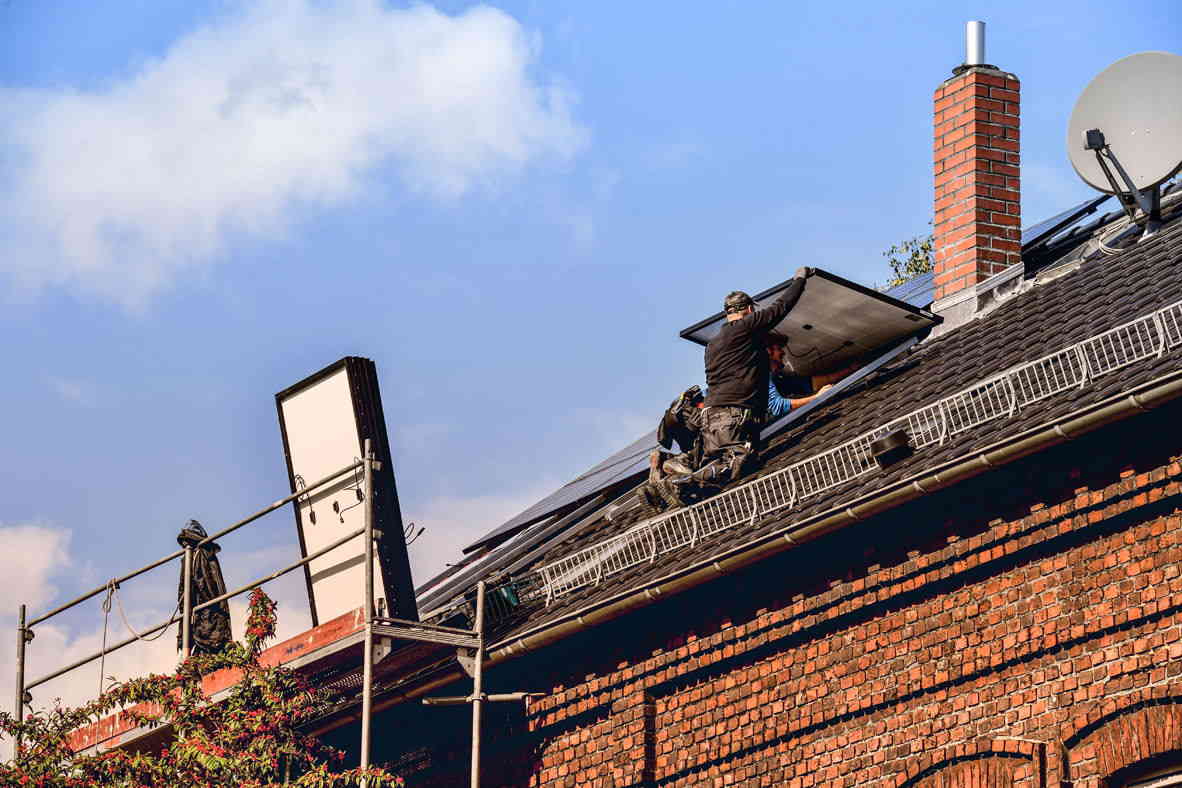 Zwei Arbeiter, die gerade eine Photovoltaikanlage anbringen.