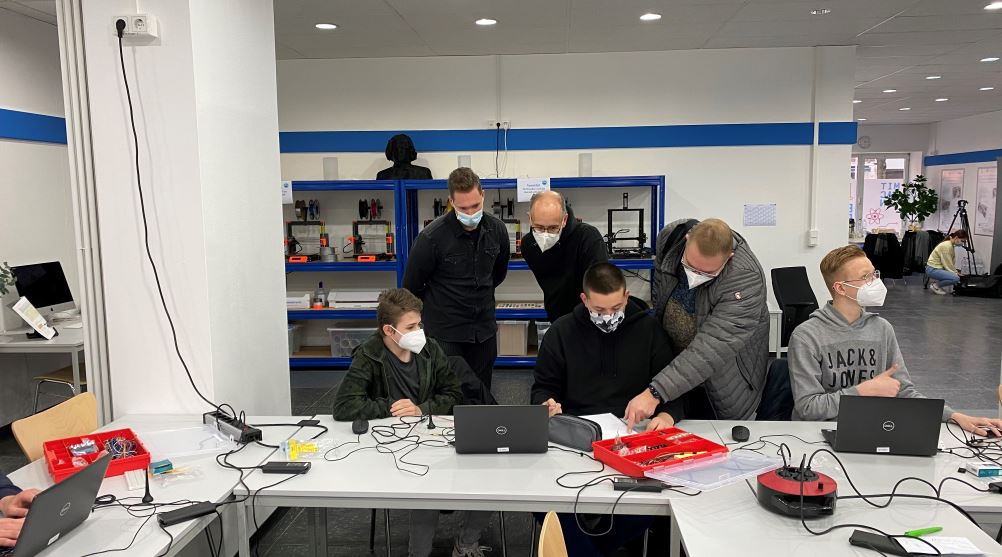 Mehrere Schüler, die im Labor sitzen und an Laptops arbeiten.