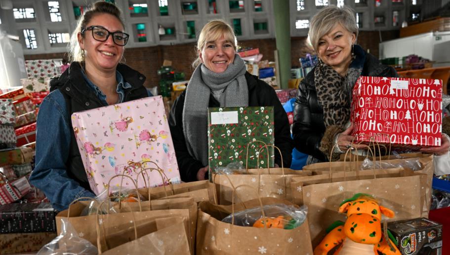 Drei Frauen, die mit mehreren vollgepackten Geschenktüten posieren. 